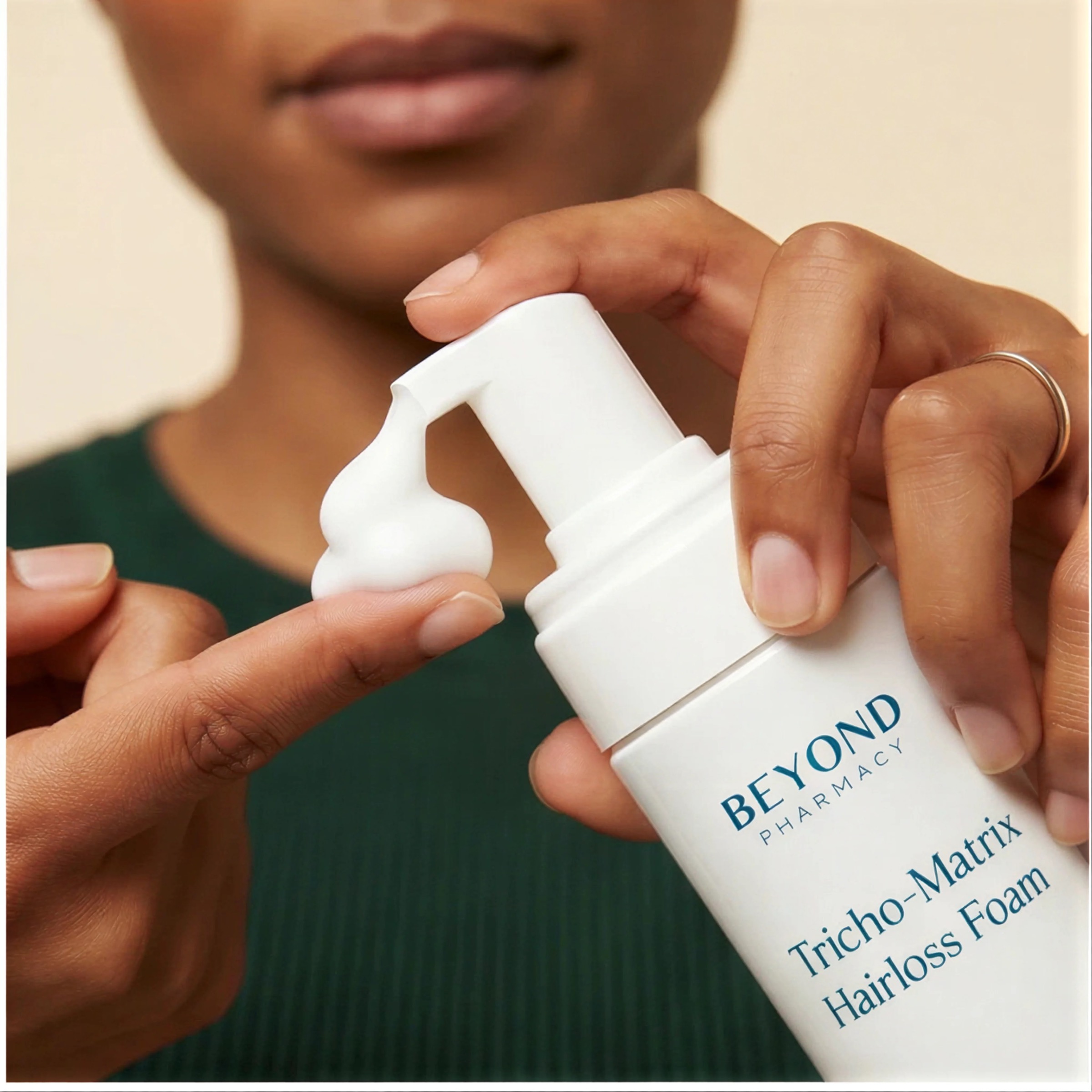 Trichofoam propylene glycol-free topical finasteride foam being dispensed onto a fingertip